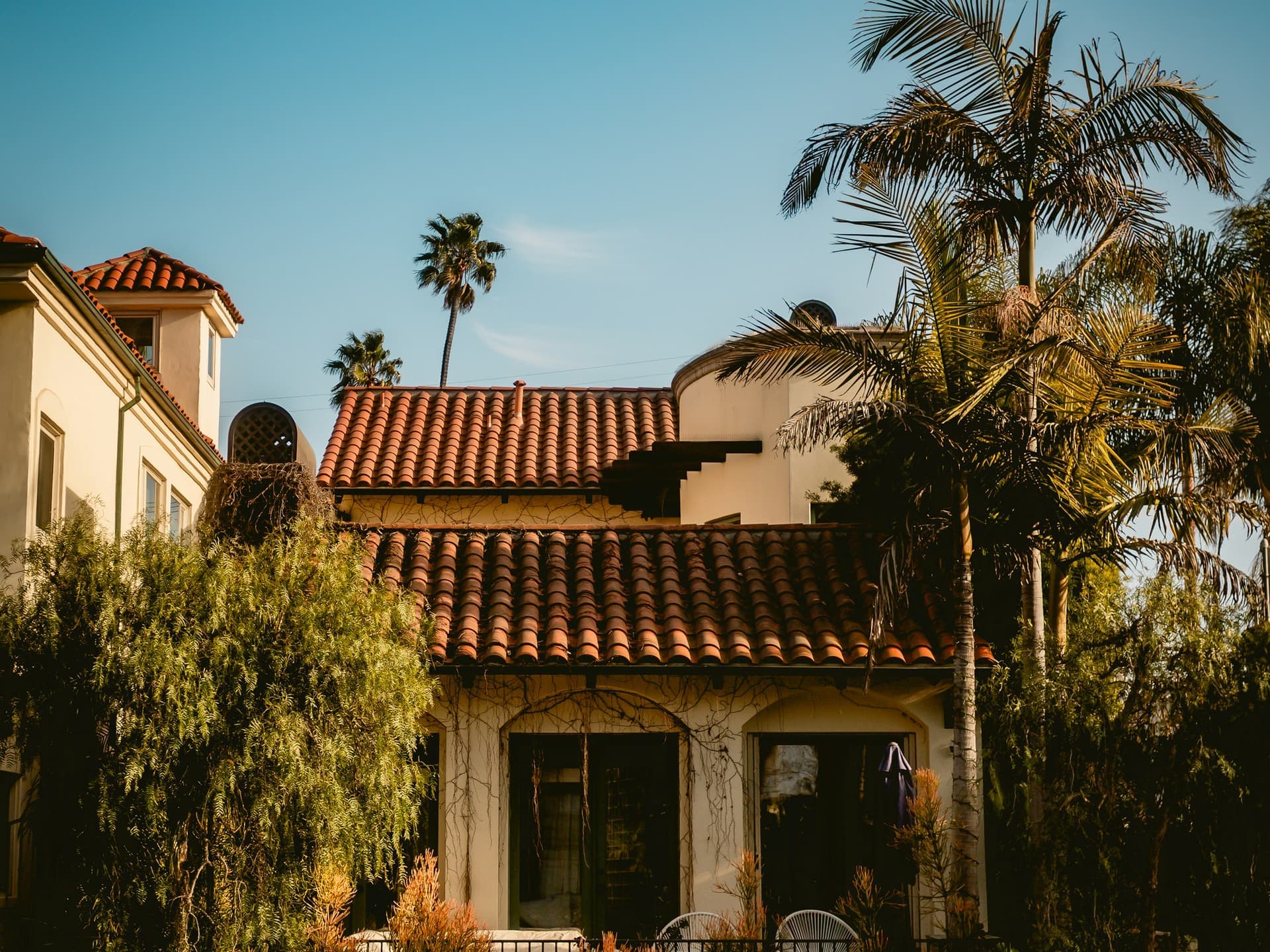 Mediterranean-style house with a red tile roof and palm trees